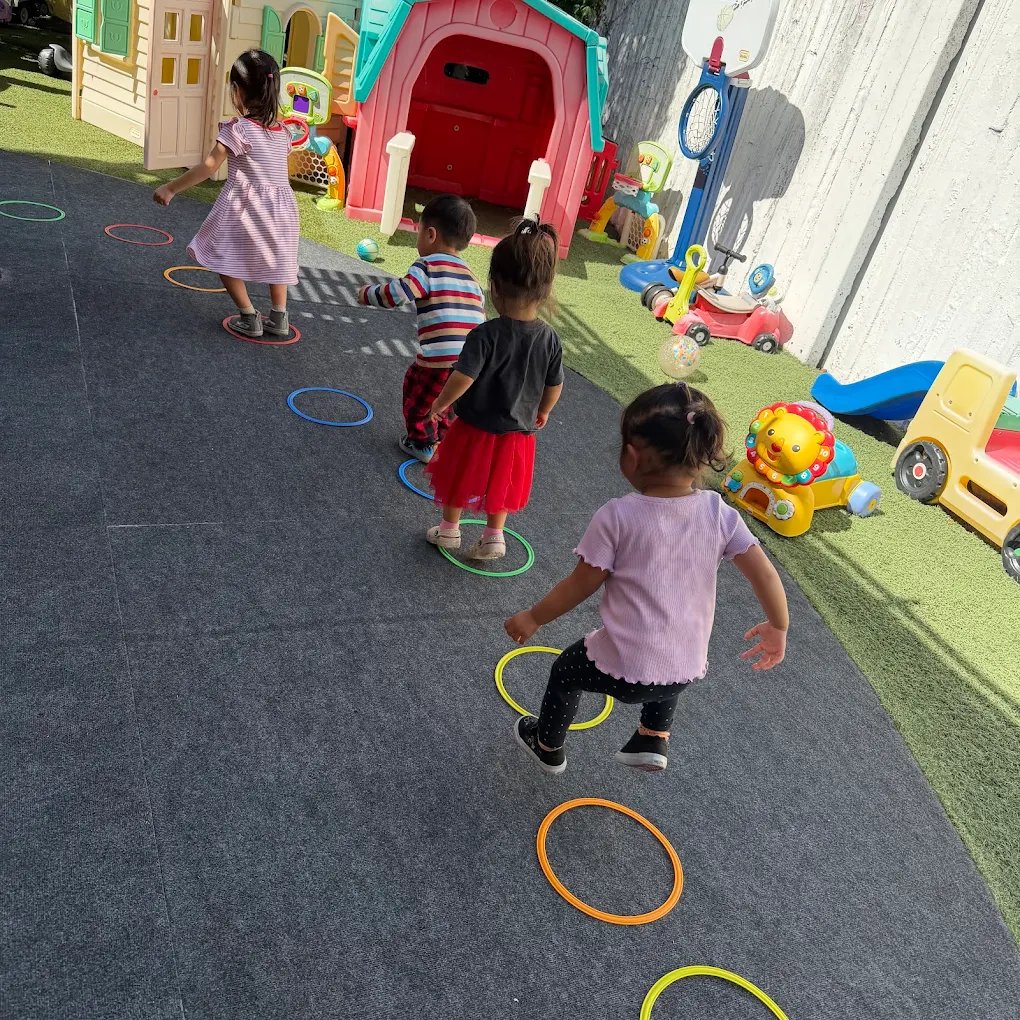 Children hopping through colorful hoops during outdoor play at Crayoland