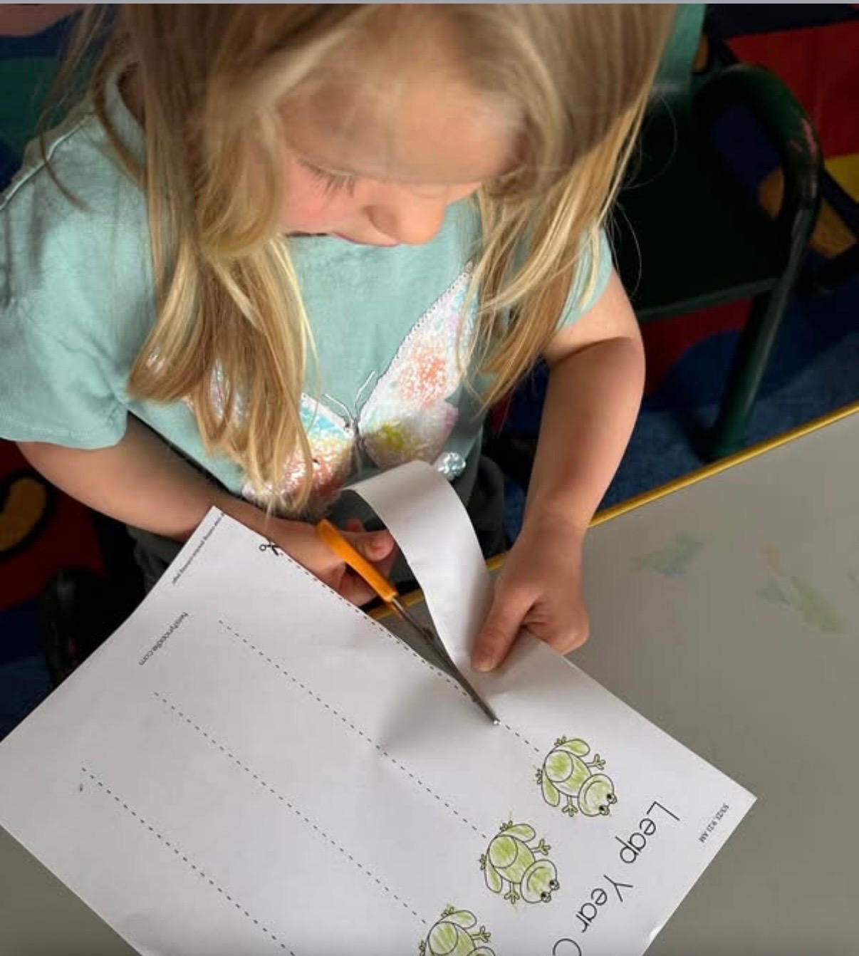 Child practicing scissor skills on a leap year cutting worksheet