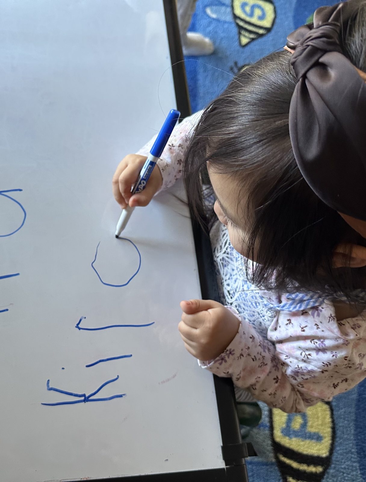 Child practicing writing letters on the whiteboard